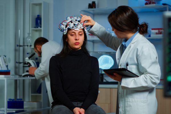 Professional doctor in neuroscience developing treatment for neurological diseases examining patient evolutions. Doctor researcher adjusting EEG headset analyzing brain functions and health status